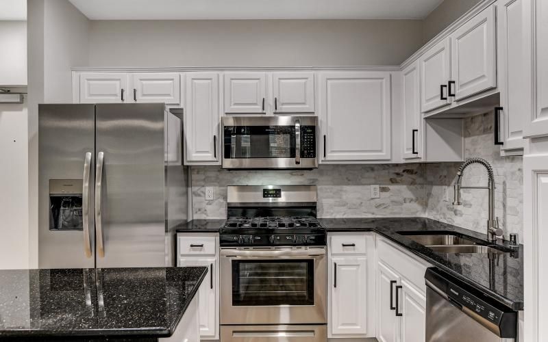 a kitchen with white cabinets and stainless steel appliances
