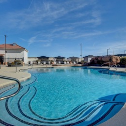 resort style pool with seating trees and a building behind it