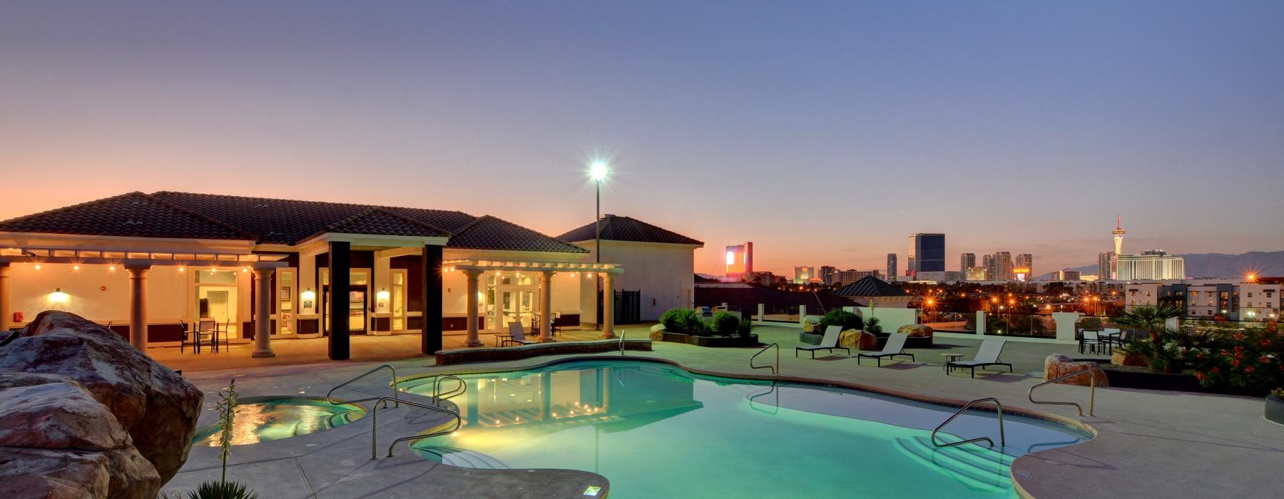 a pool in a courtyard with a city in the background at dusk