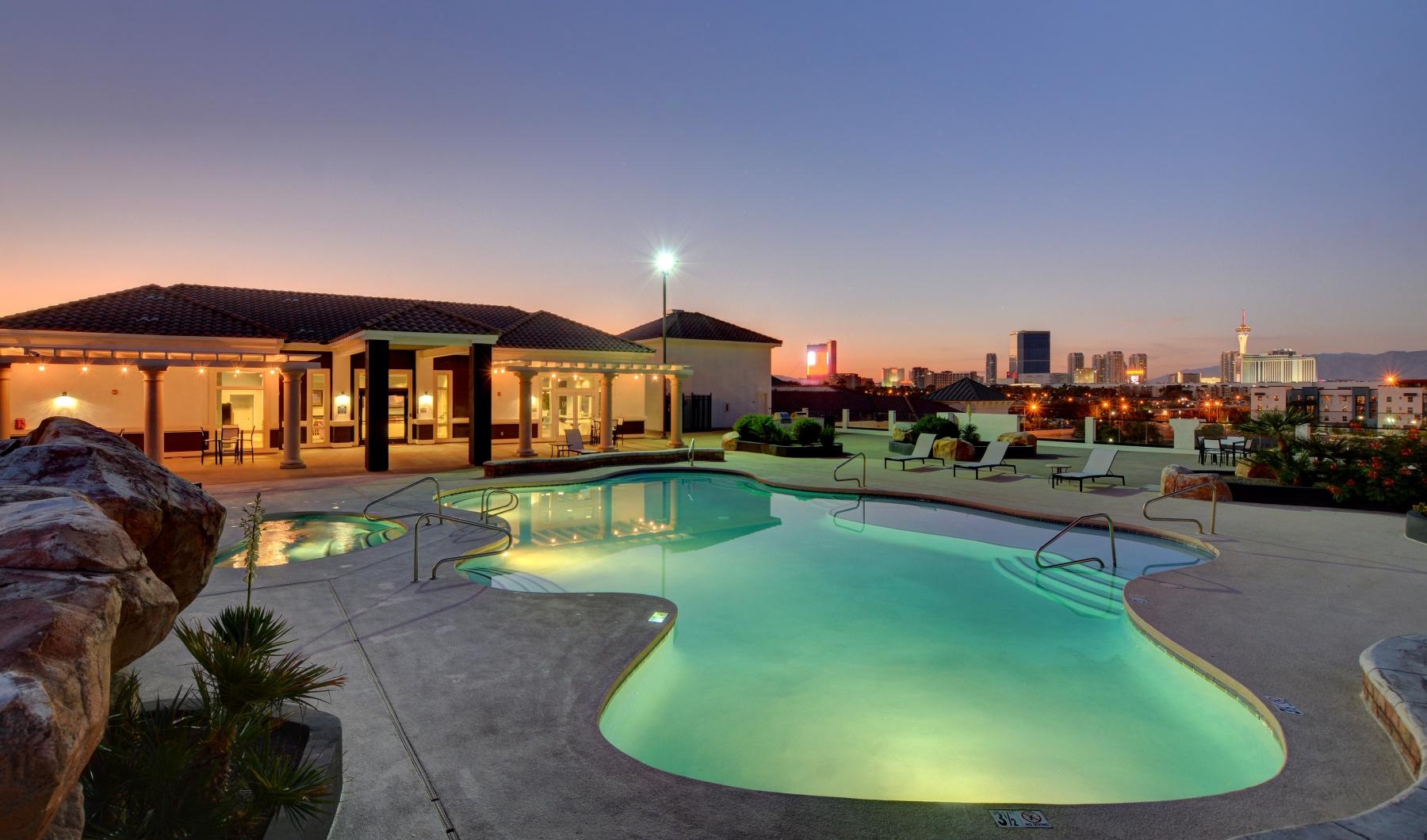 a pool in a courtyard with a city in the background at dusk