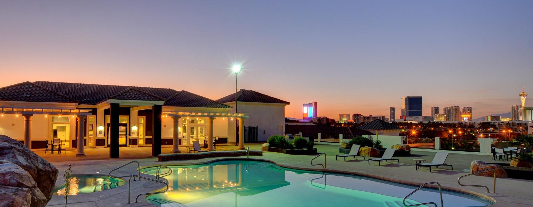 a pool in a courtyard with a city in the background at dusk
