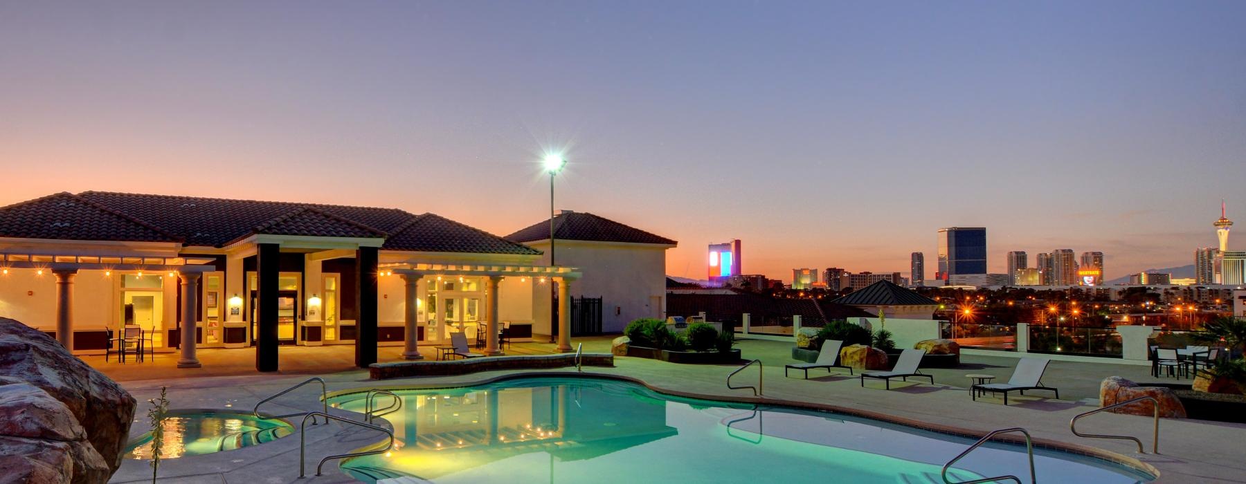 a pool in a courtyard with a city in the background at dusk